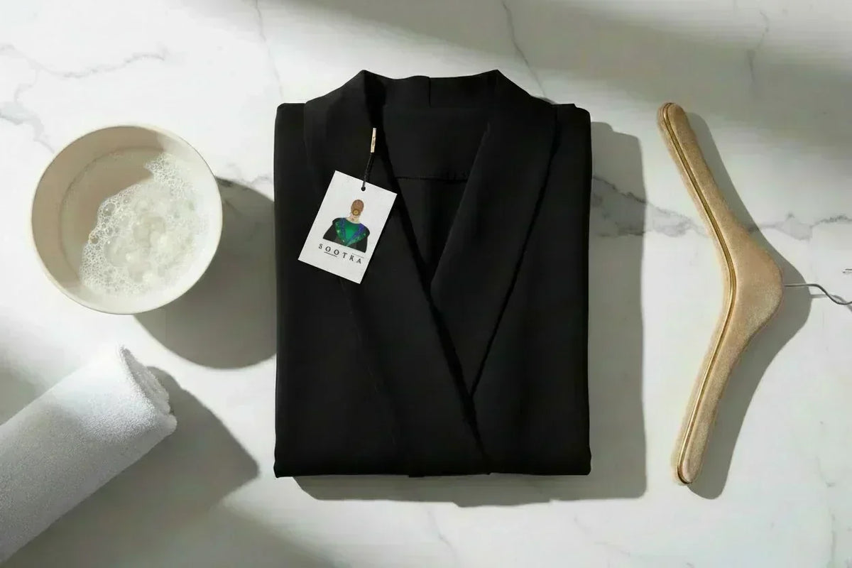 Entretien abaya en crêpe : bassine d'eau savonneuse, cintre luxe et étiquette SOOTRA — guide lavage abaya et bisht SOOTRASHOP